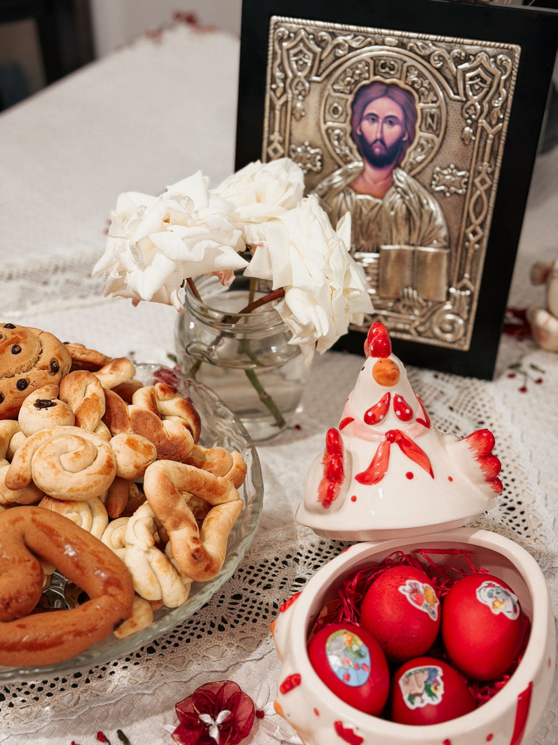 A table set for Orthodox Easter with cookies, dyed eggs, and religious icon.