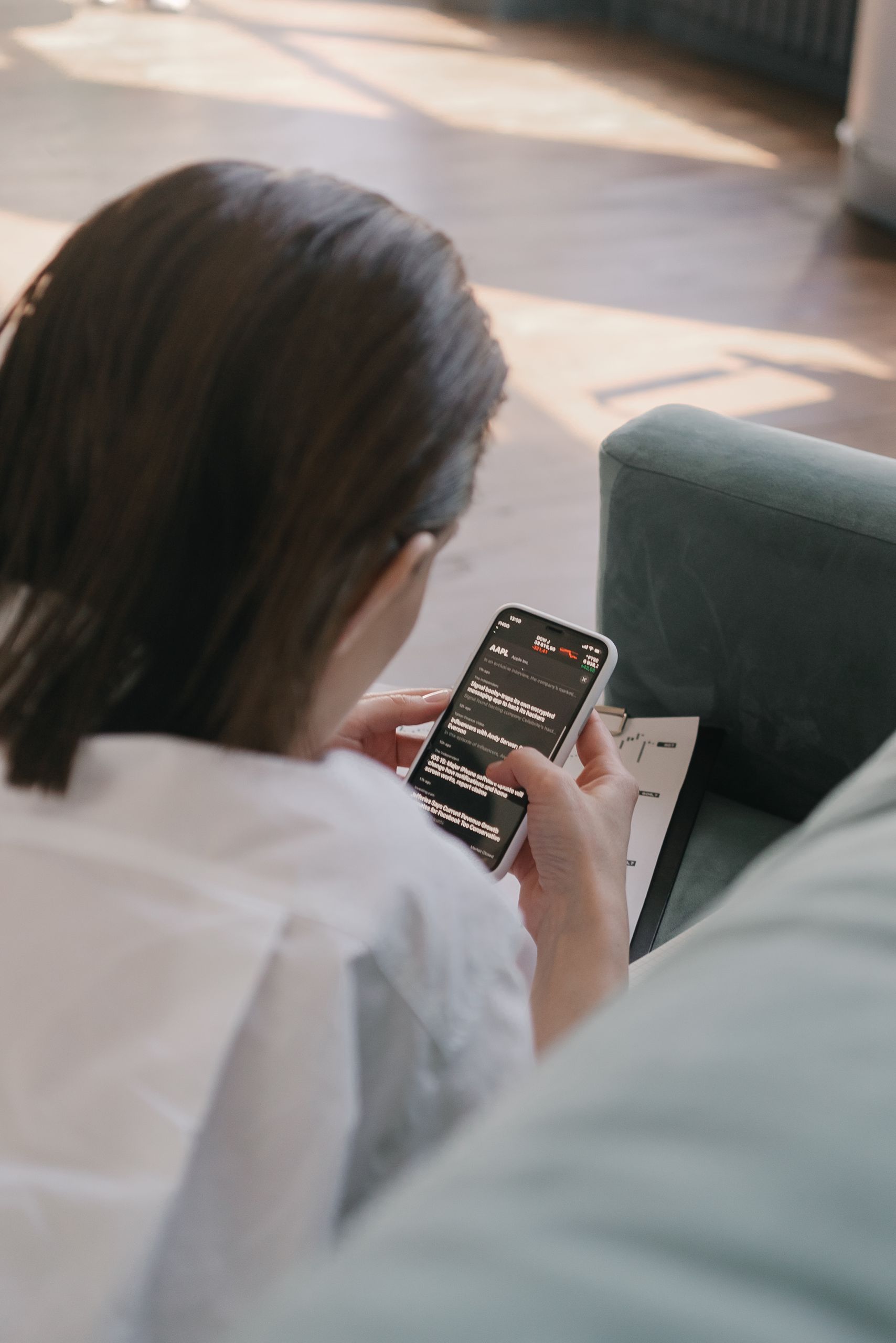 A woman uses her smartphone inside, viewed from behind. Perfect for lifestyle or technology themes.