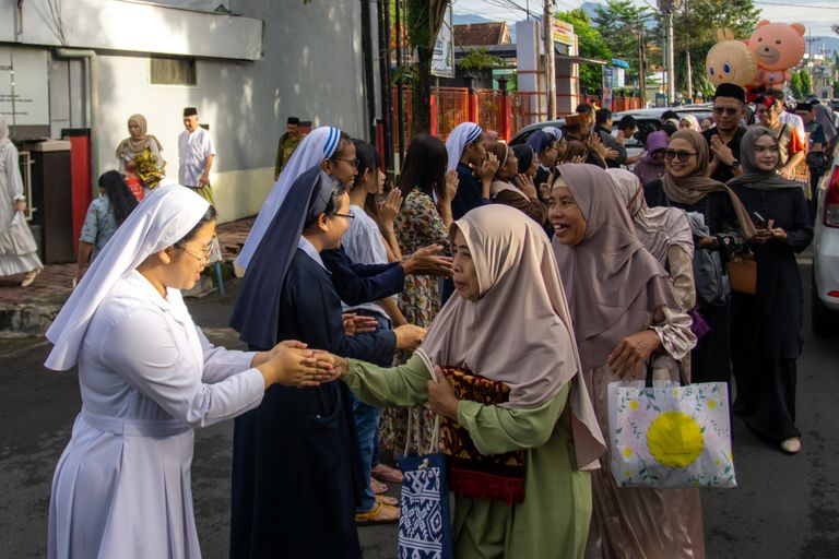 Interfaith gathering with nuns and Muslim women greeting each other in Indonesia.