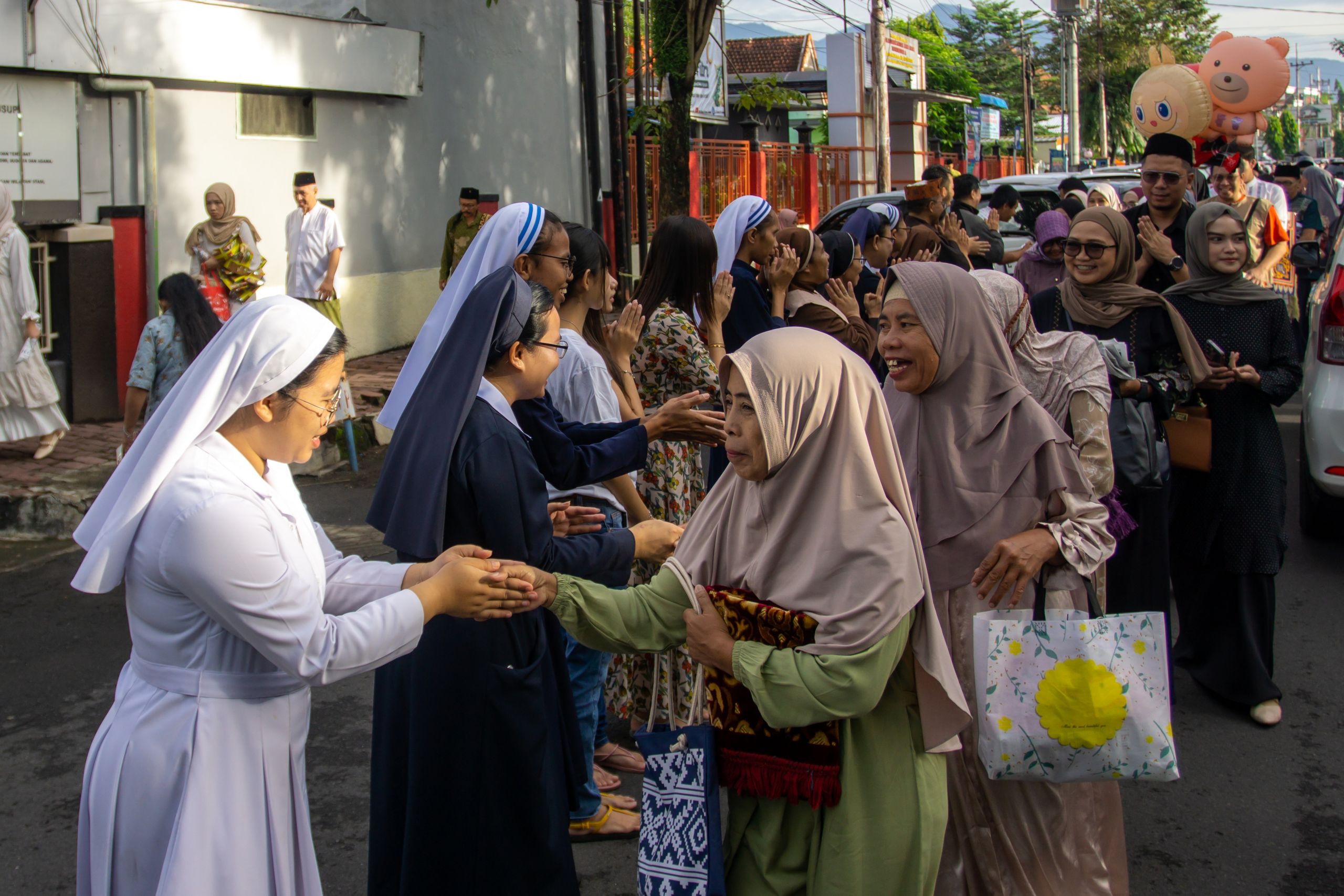 Interfaith gathering with nuns and Muslim women greeting each other in Indonesia.